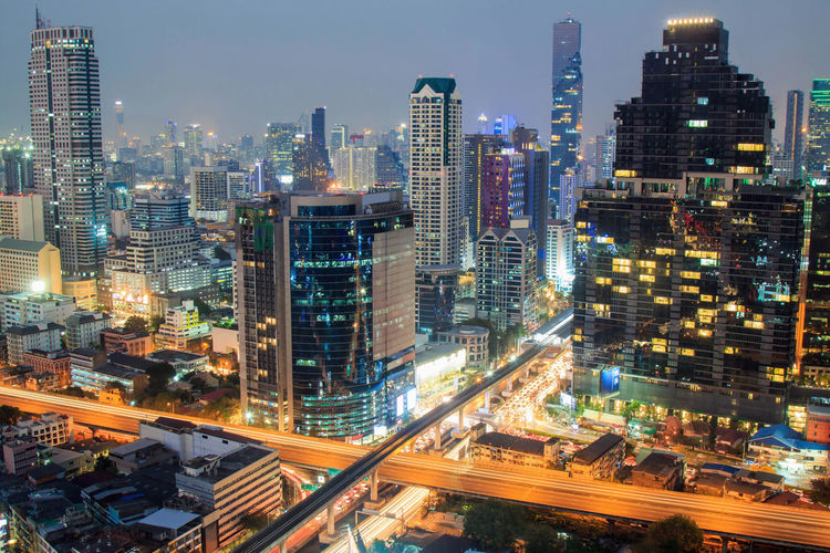 Aerial view of bangkok buildings urban city downtown at night with car light on the street.