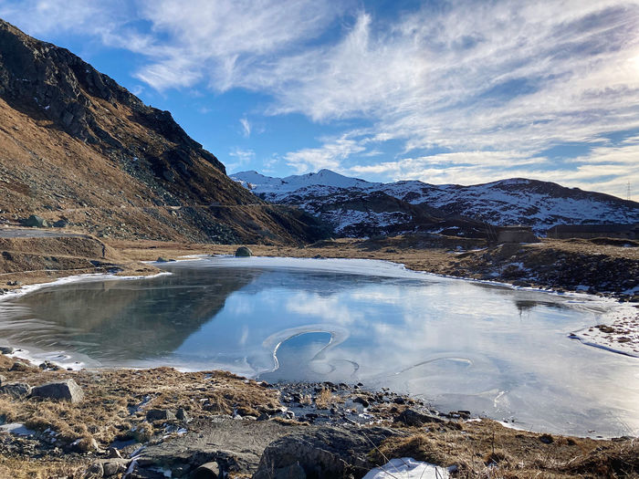 Scenic view of lake by snowcapped mountains against sky, passo del san gottardo, ticino 