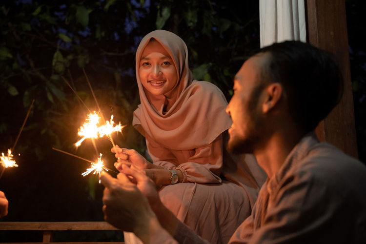 Happy couple holding sparkler at night