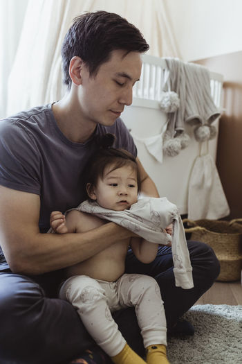 Father changing clothes of baby son at home