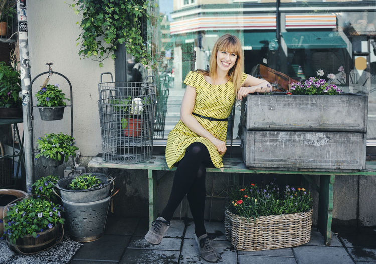 Portrait of happy owner leaning on crate outside plant shop