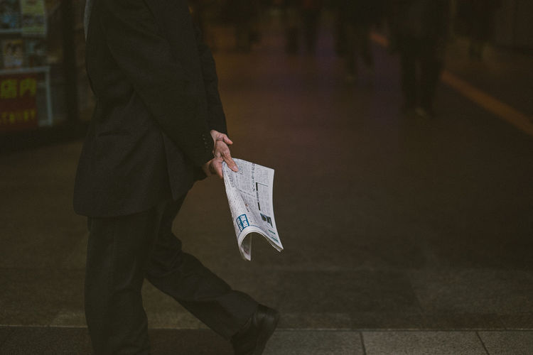 Man holding newspaper while walking outdoors