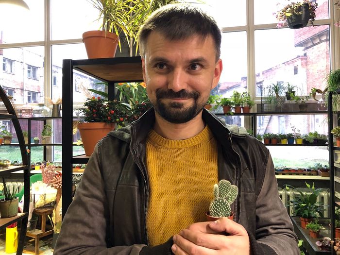 Man looking away while holding succulent plant at store