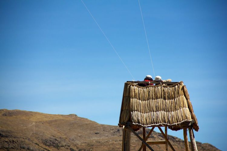 Low angle view of people on tower against blue sky