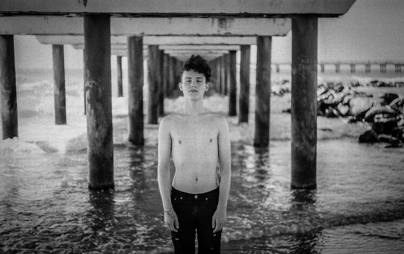 Shirtless young man standing at beach