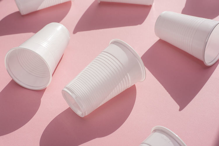 High angle view of disposable cups against pink background