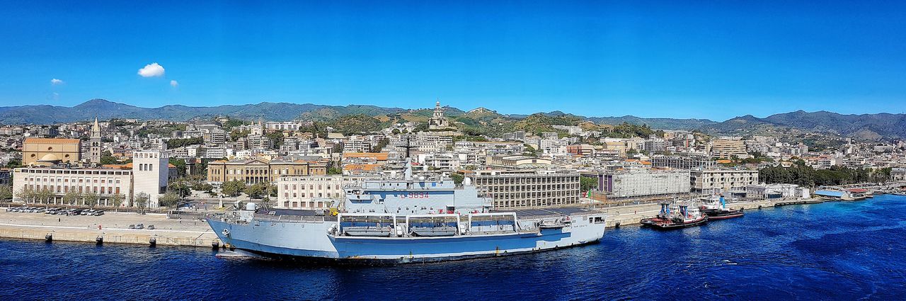 Aerial view of city by sea against blue sky