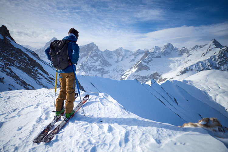Man on skis on ridge looking at mountain view