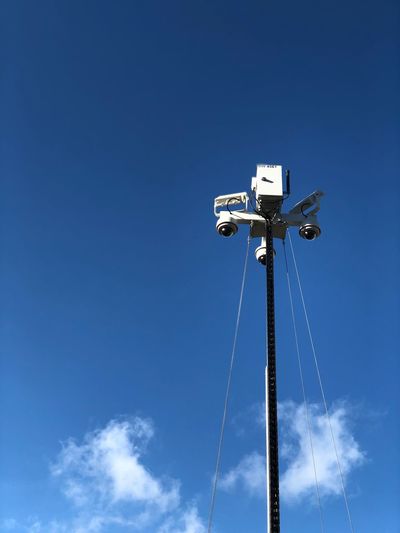 Low angle view of security cameras against blue sky