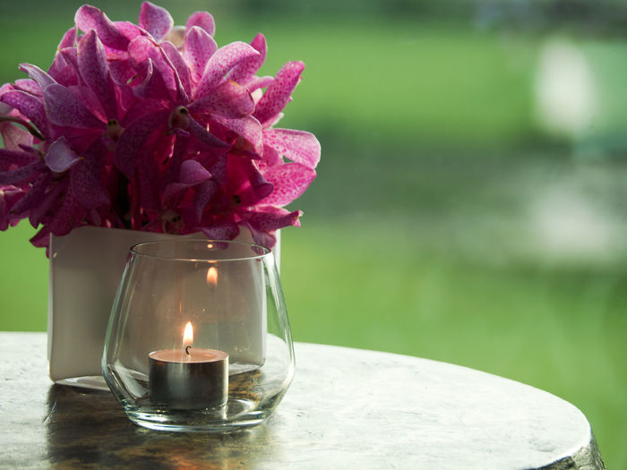 Thai orchids in vase and candle light in glass for decoration on the table.
