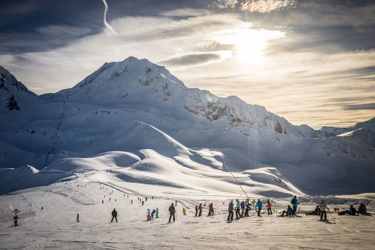 Group of people skiing on snow against mountain