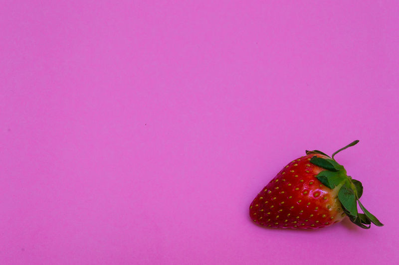 Close-up of strawberry over pink background