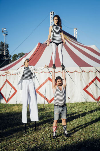 Acrobats performing with artist while standing on meadow