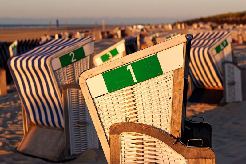 Hooded beach chairs at beach during sunset