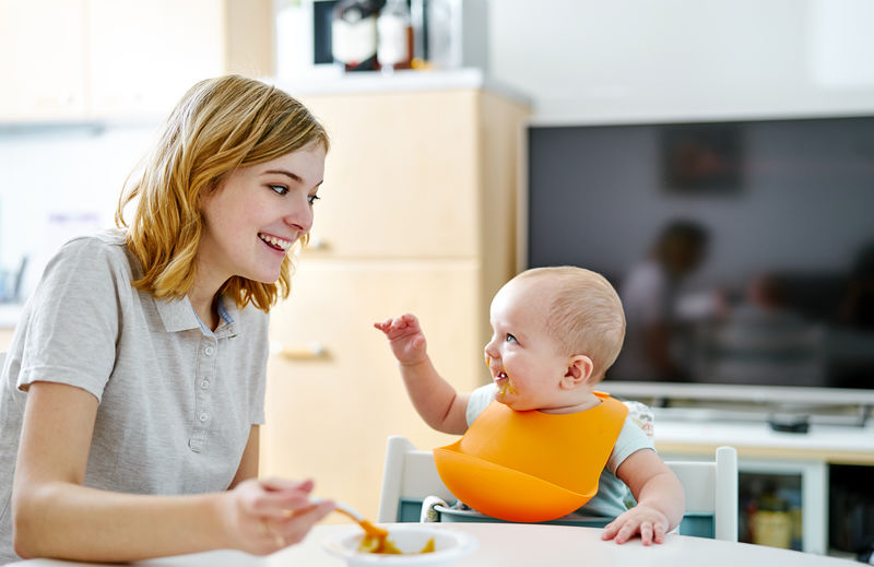 Smiling mother feeding son at home