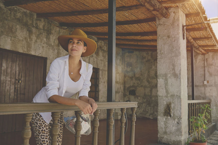 Woman wearing cowboy hat sitting on porch, jalisco mexico, portrait of happy woman using hat. 