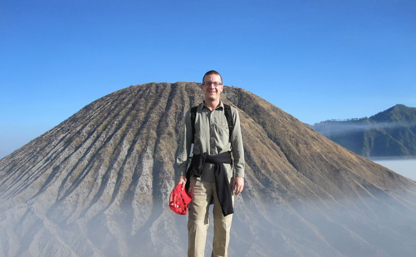 Portrait of man standing against mountain and clear blue sky