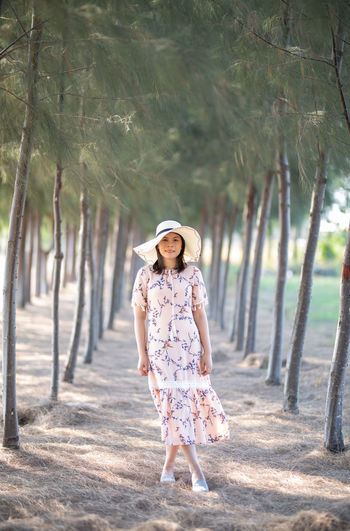 Portrait of woman standing amidst trees at beach