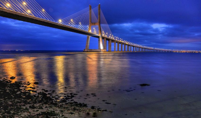 Vasco da gama bridge over tagus river against cloudy sky at dusk