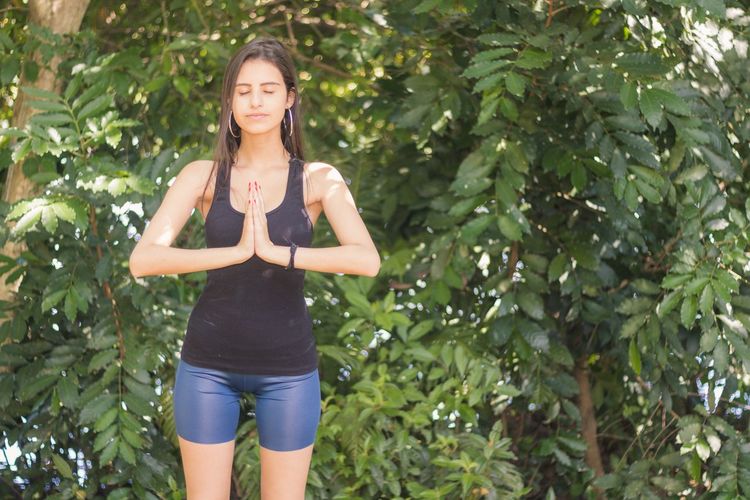 Young woman with eyes closed doing yoga in forest