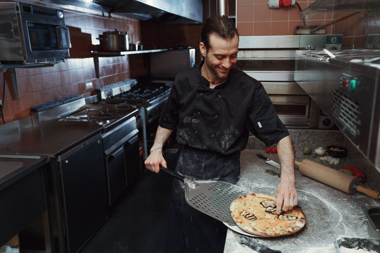 Male chef preparing italian pizza in kitchen
