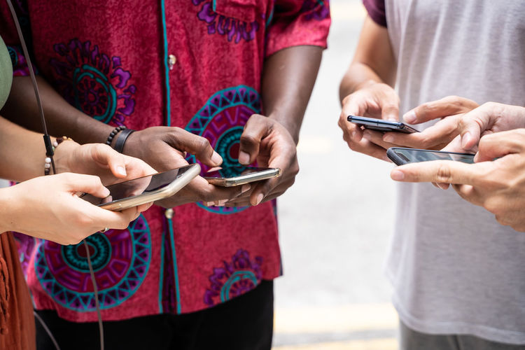 Midsection of men and woman holding mobile phones