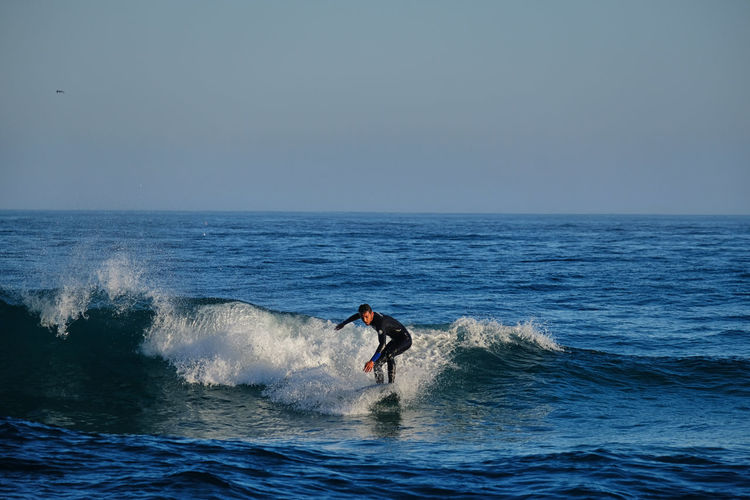 Man surfing on sea against clear sky