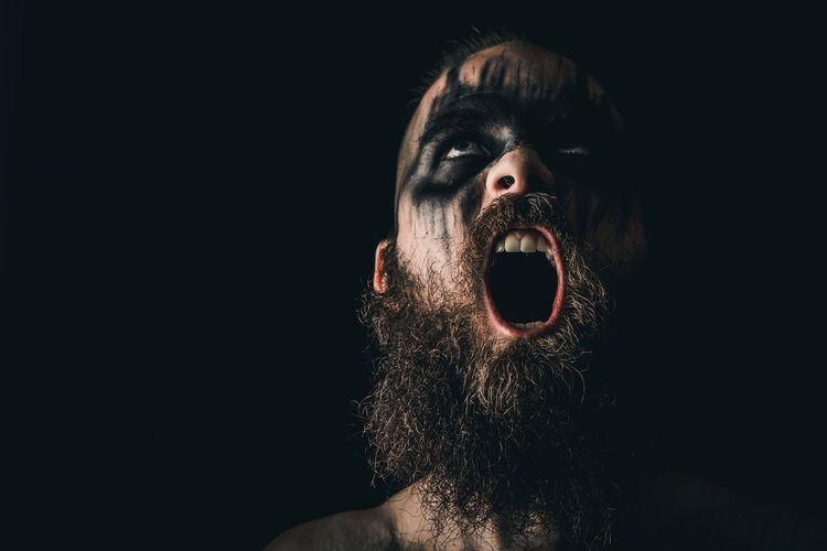Portrait of a viking warrior with black war paint, screaming with rage and anger