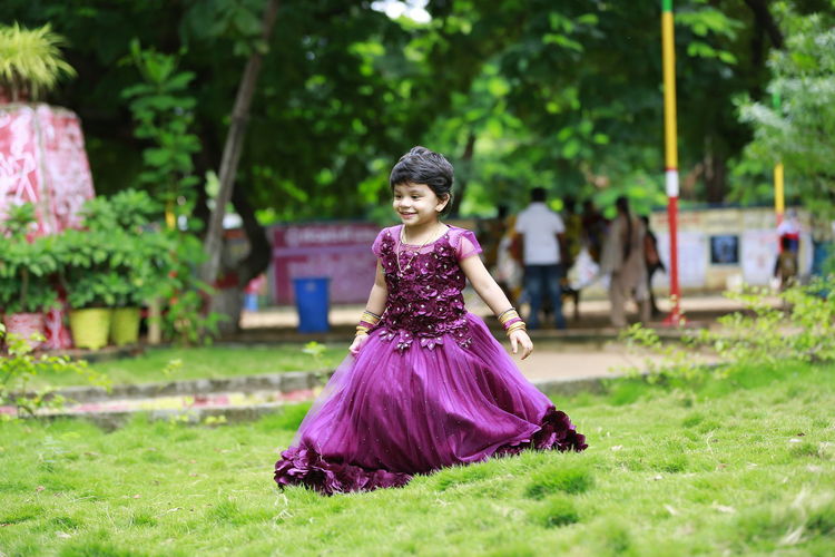 Full length of girl wearing purple flower on field