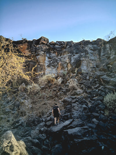 Rear view of person on rock against sky