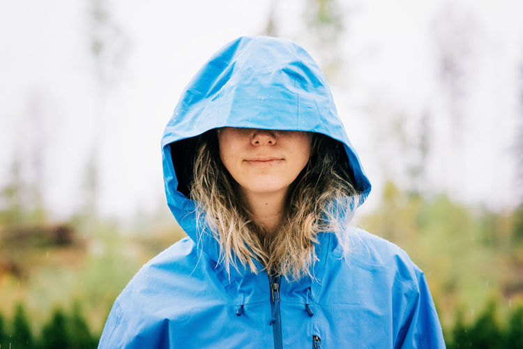 Woman standing in the rain with her hood over her eyes