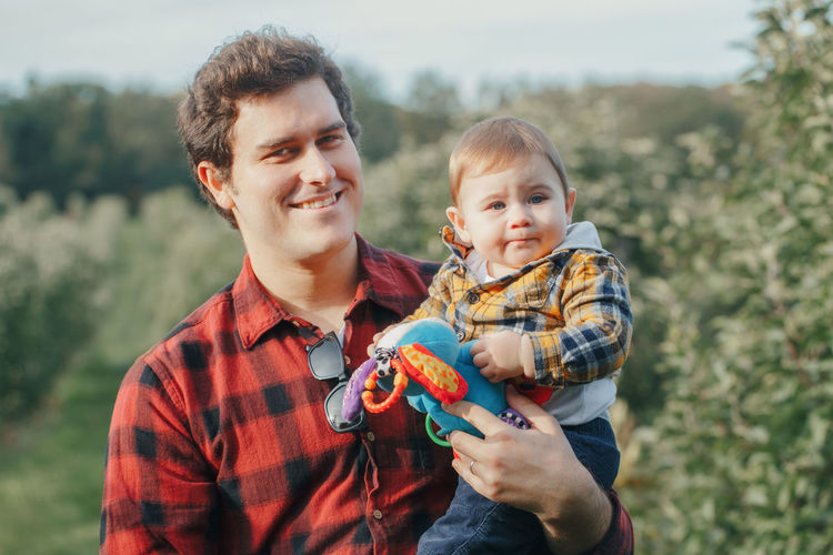 Caucasian father hugging playing with baby boy. parent holding carrying child son outdoor. 