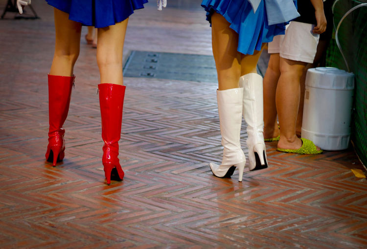 Low section of women in latex boots walking at footpath