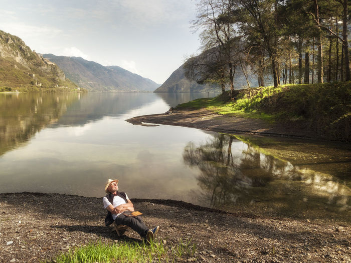 Italy, lombardy, senior man relaxing at lake idro