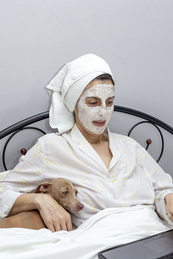 Close-up of woman wearing bathrobe sitting with dog