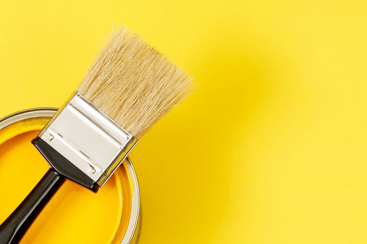 High angle view of paintbrush against yellow background