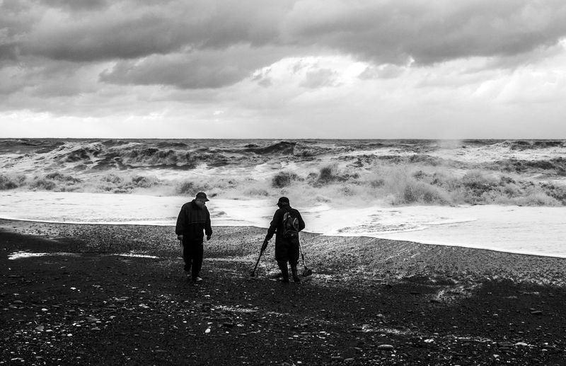 Men walking on beach against sea