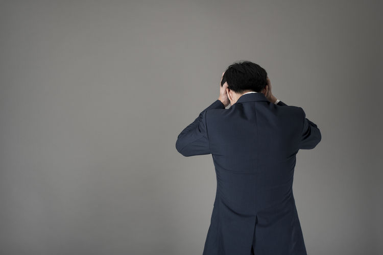 Stressed businessman standing against gray background