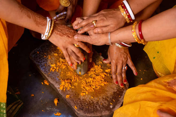 High angle view of women crushing turmeric on stone