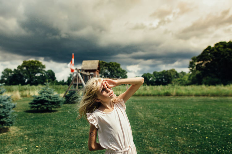 Girl facing the sky on a windy and cloudy day