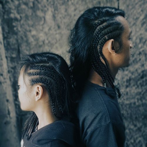 Side view of friends with braided hair standing by wall