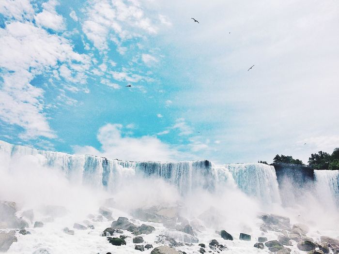Scenic view of waterfall against cloudy sky