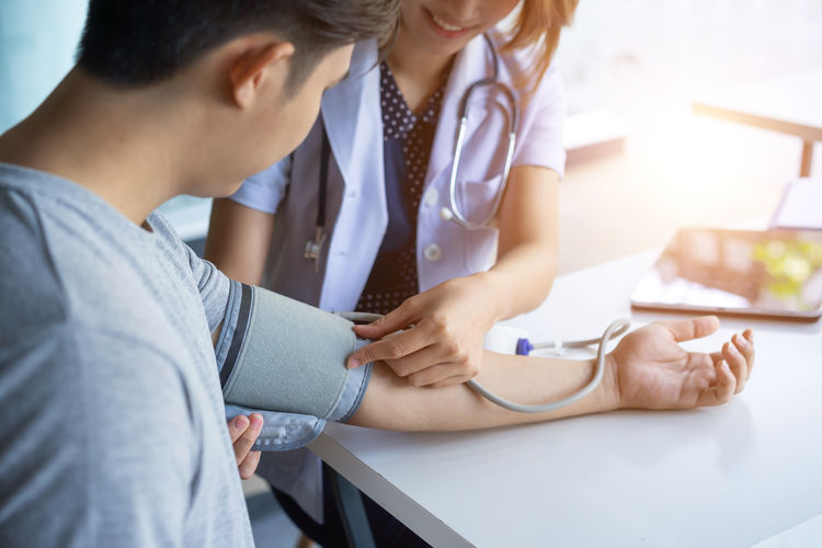 Midsection of doctor examining patient while sitting on table