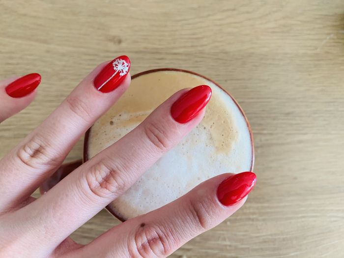 Close-up of hand holding red cup on table