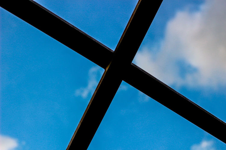 Low angle view of glass window against blue sky