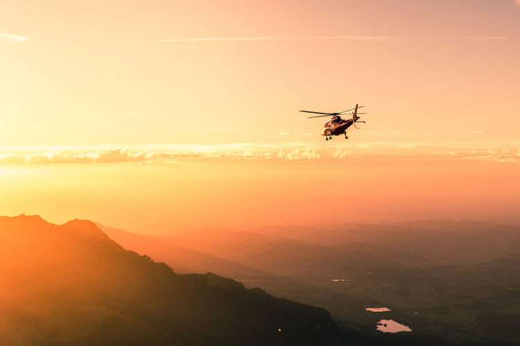 Helicopter flying against sky during sunset