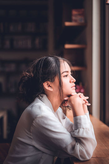 Side view of thoughtful woman sitting in coffee shop