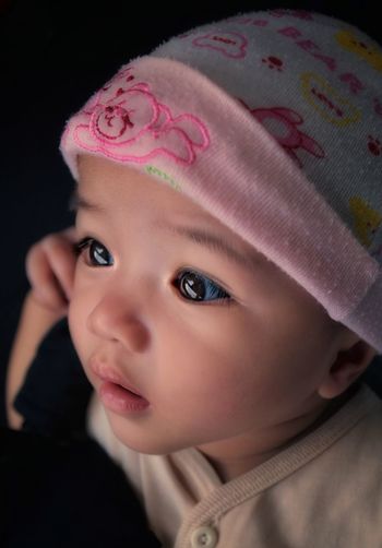 Cute baby girl looking away against black background
