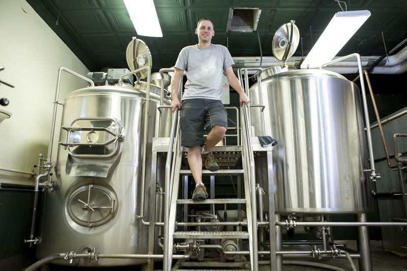 Low angle portrait of confident businessman standing against storage tanks at winery