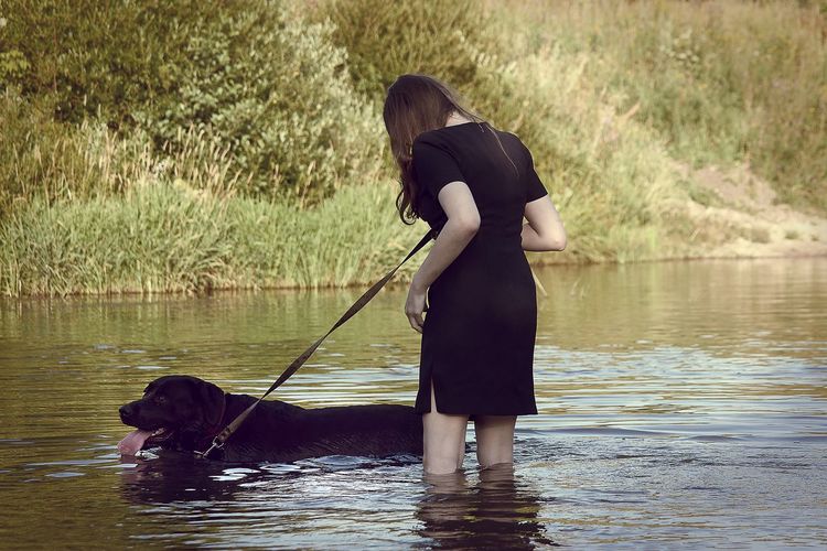 Woman with dog standing in lake